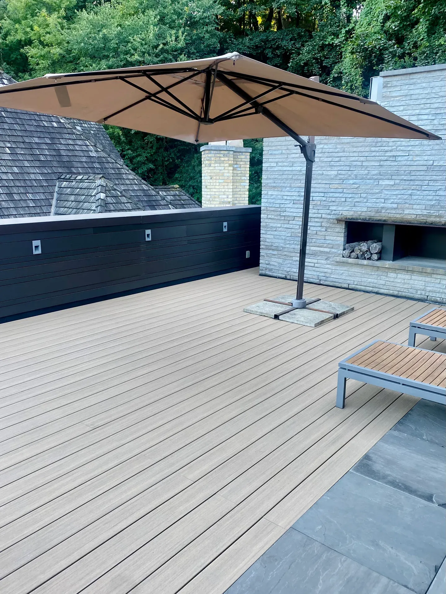 Pale AZEK deck boards on a furnished rooftop terrace with an umbrella and outdoor fireplace