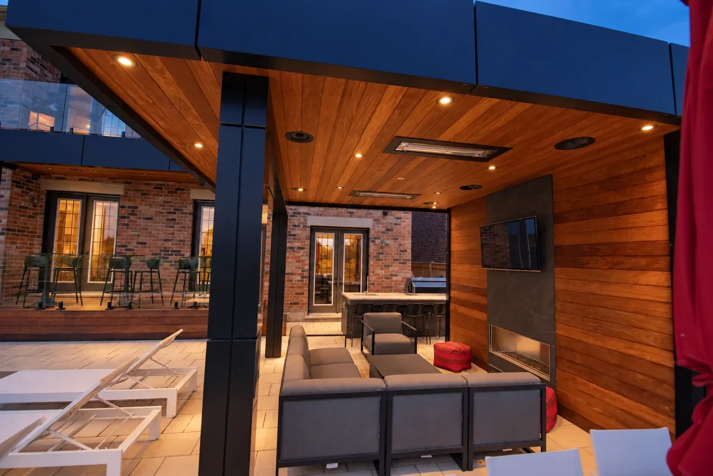 Warm recessed downlights illuminate a wood-lined cabana and outdoor lounge at dusk; lighting visualization based on a real project