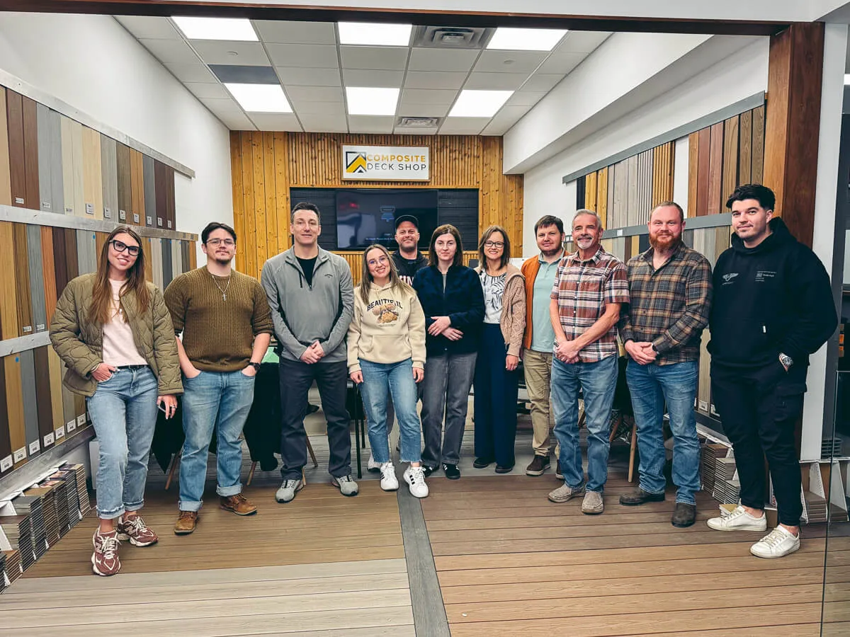 Composite Deck Shop team standing together in the showroom among decking displays