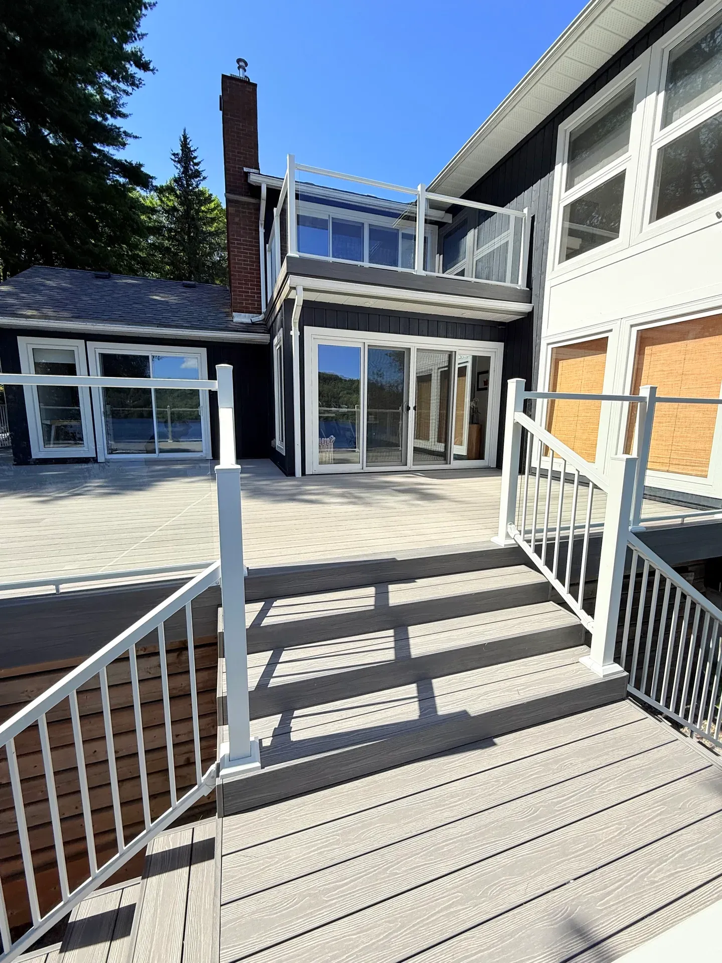 Broad deck stairs joining two levels beside a cottage, with pale picket railings