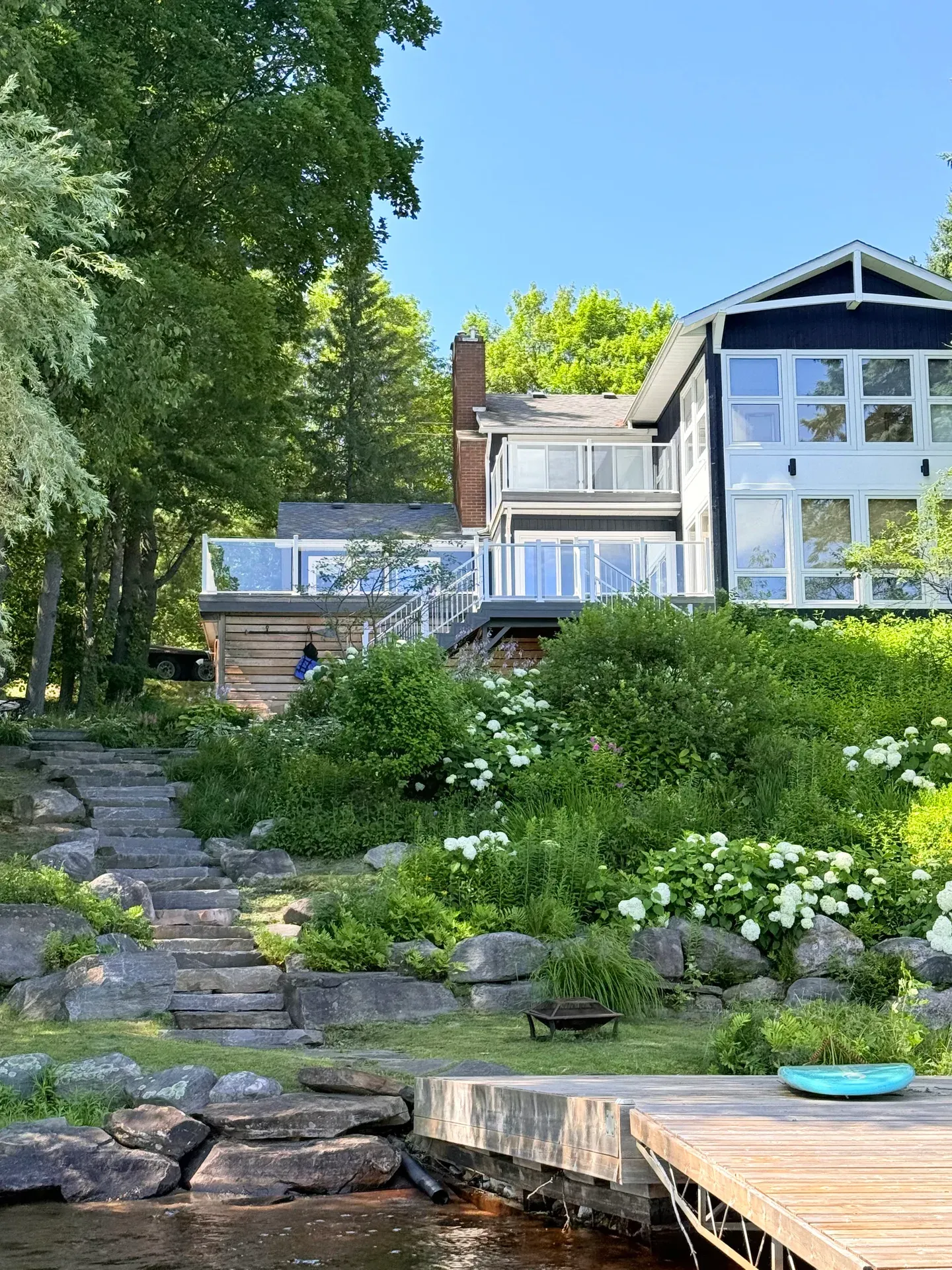 Cottage deck and stairs above a planted sloping garden leading to the waterfront