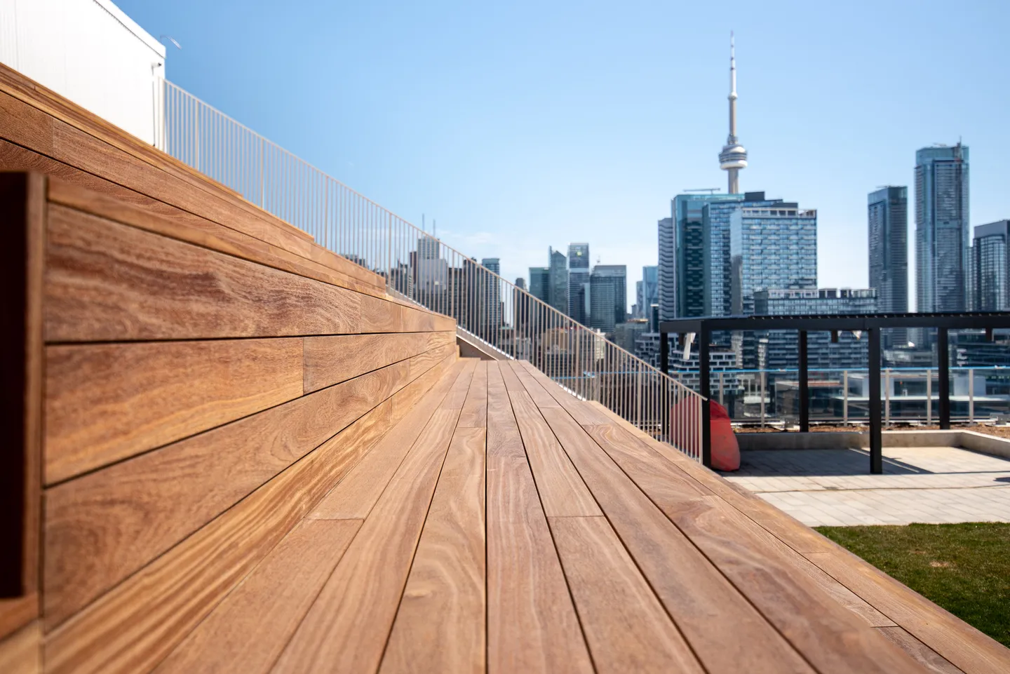 Cumaru boards running toward the Toronto skyline on a finished condo terrace, the wood holding a warm golden-brown tone
