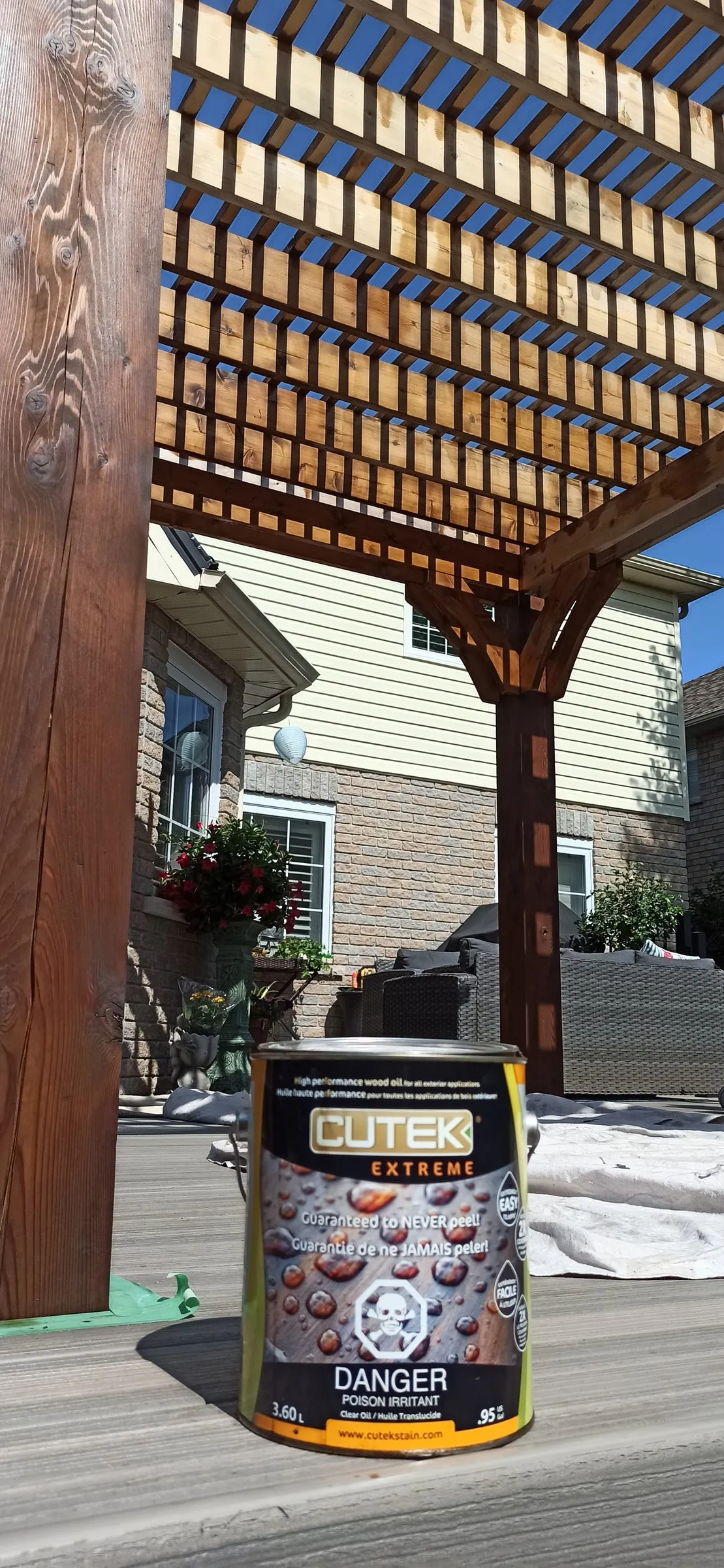 Can of CUTEK Extreme wood oil standing on deck boards beneath a pergola.