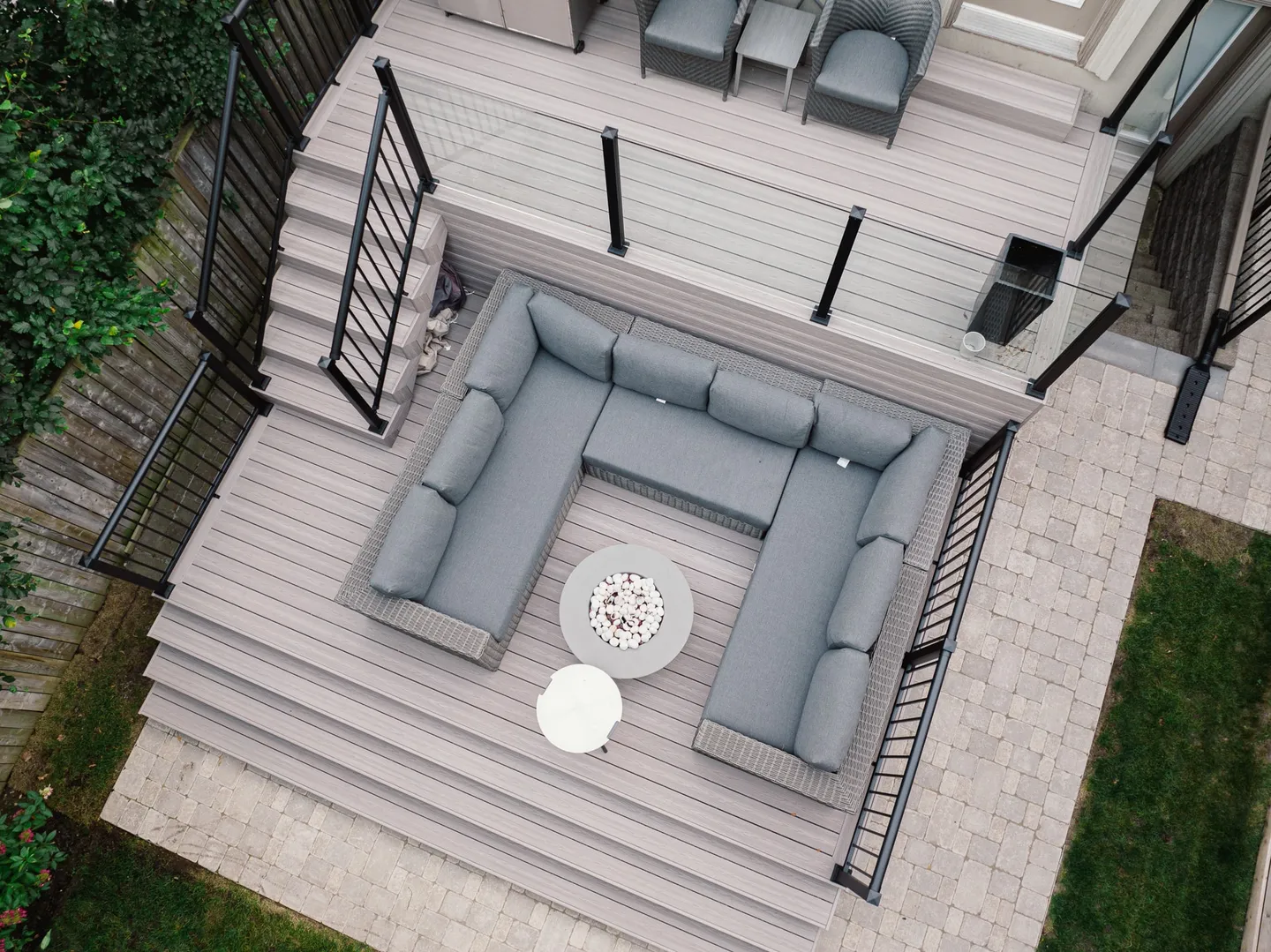 Overhead view of a two-level Fiberon deck with picture-frame borders, wide stairs, glass panels and black picket railings