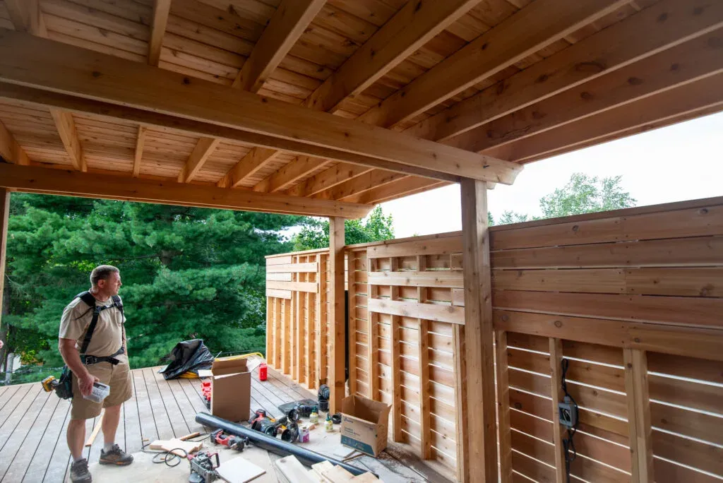 Delta Decks builder working with tools on a covered rooftop deck during construction