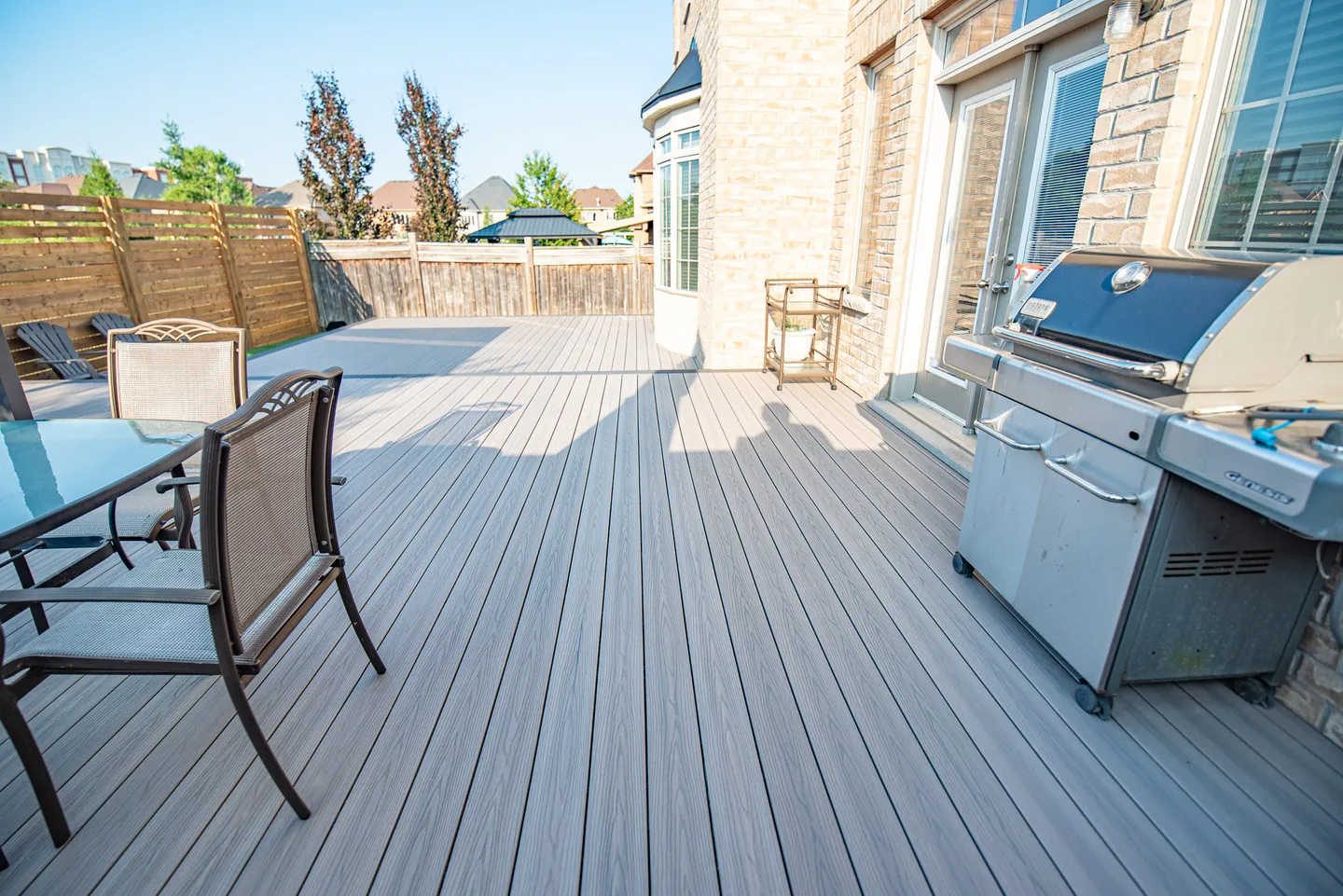 Grey composite decking beside a dining table, barbecue and timber privacy screen