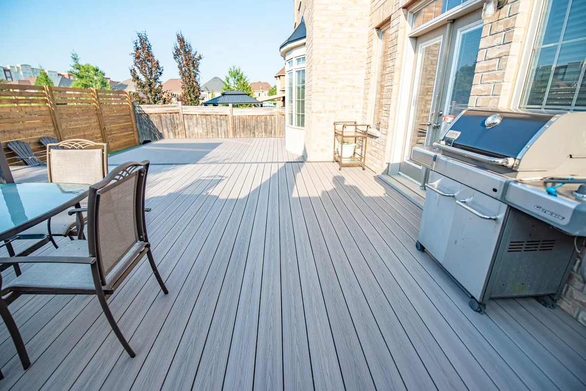 Grey composite decking beside a dining table, barbecue and timber privacy screen