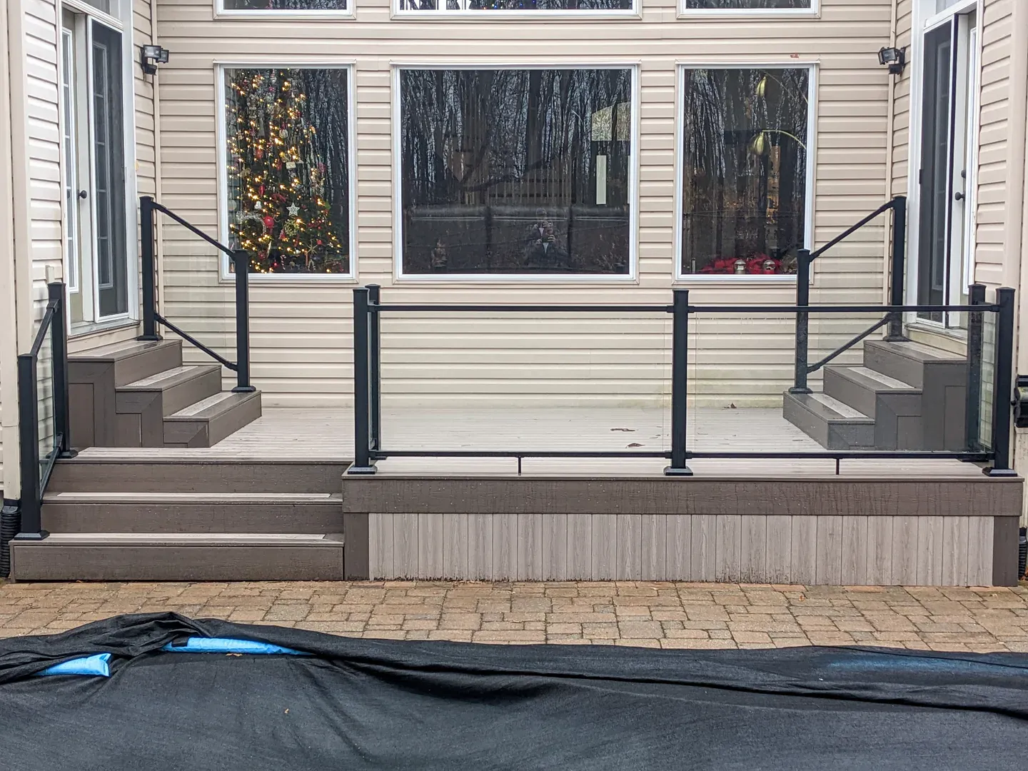 Clear glass railing panels and black posts enclosing a low deck with steps at both ends