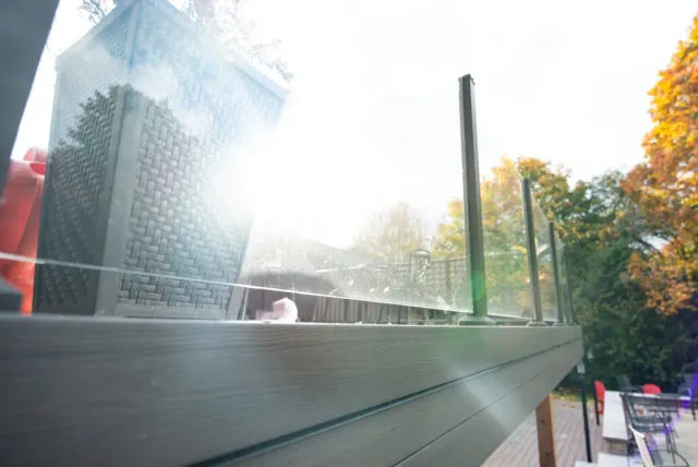 Close view of glass railing posts and fascia at an elevated deck edge