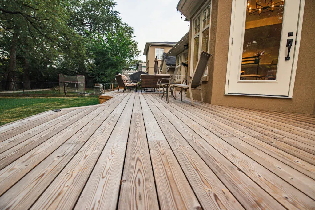Close view of wood deck grain and board gaps beside a garden-facing door