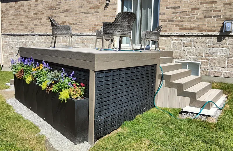 A low composite deck with a fascia band along its edge, dark lattice skirting closing the base, and a flight of composite stairs with matching treads and risers